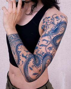 a woman with tattoos on her arm holding a cell phone