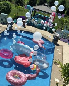 an inflatable pool is decorated with pink and white balloons, seashells, and other decorations