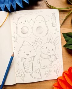 an open notebook with some drawings on it next to orange flowers and blue ornament