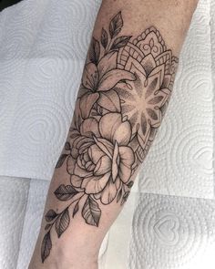 a black and white flower tattoo on the left arm, with an intricate design in the middle