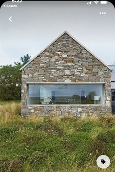 a stone building with windows and grass in front of it