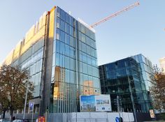 an office building is being built on the corner of a street with construction cranes in the background