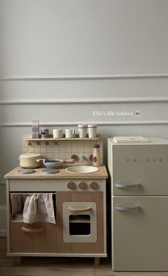 an old fashioned wooden toy stove and oven in a room with white walls, wood floors and flooring