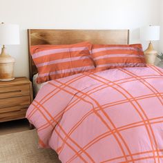 an orange and pink comforter on a bed in a room with two lamps next to it