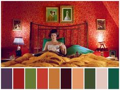 a woman sitting on top of a bed in front of a red wall with pictures above it