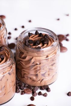 three glass jars filled with chocolate desserts and coffee beans on top of a white surface