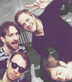 four young men are posing for the camera with their hands in the air and smiling