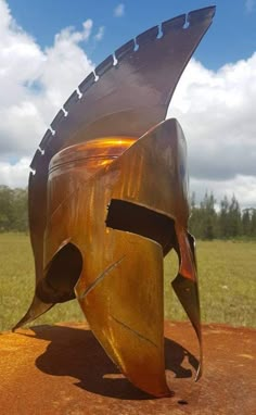 a sculpture in the shape of a fish on top of a dirt mound with grass and blue sky behind it