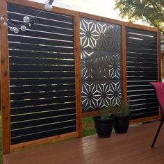 a wooden deck with two planters and a privacy screen on the side of it