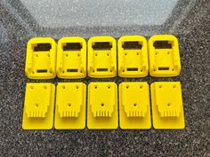 eight yellow plastic clips are lined up on the floor next to each other, all with holes in them