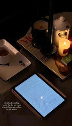 a tablet computer sitting on top of a table next to a cup of coffee and candle