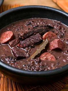 a bowl filled with beans and meat on top of a wooden table