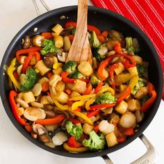 a skillet filled with stir fry vegetables on top of a white counter next to a red towel