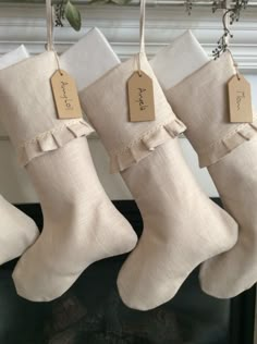 three christmas stockings hanging on a mantle with tags attached to the stocking, and one is for sale