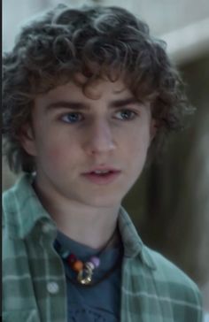 a young man with curly hair wearing a green shirt