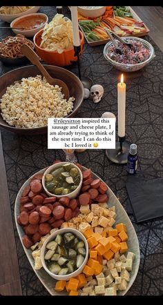 a table topped with bowls filled with food next to a candle and some plates full of food