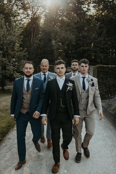 a group of men in suits walking down a road