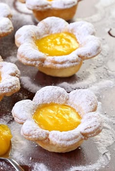 small pastries are covered in powdered sugar and decorated with yellow frosting flowers