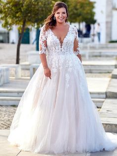 a woman in a white wedding dress standing on the steps smiling at the camera with her hands behind her back