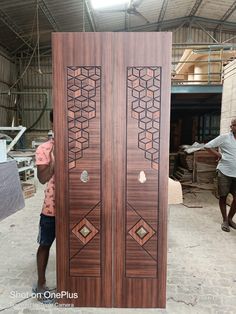 two people standing next to a large wooden door in a building with another person looking at it