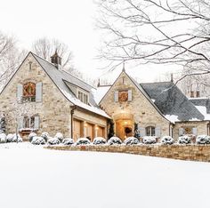 a stone house in the winter with snow on the ground and trees around it's edges