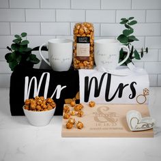 a couple of mugs sitting on top of a table next to some snacks and coffee