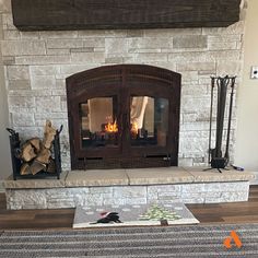 a fire place in the middle of a living room with logs on the floor next to it