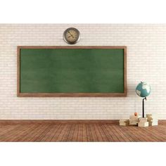 an empty classroom with a green chalkboard and books on the floor next to it