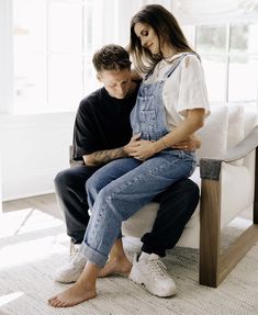 a man sitting on top of a woman's lap while they both look at each other