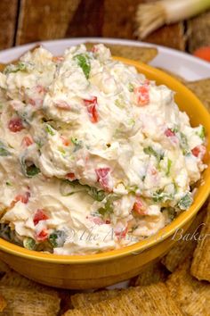 a yellow bowl filled with potato salad next to crackers