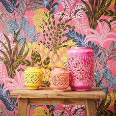 three colorful vases sitting on top of a wooden table