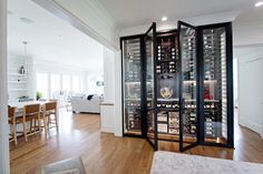 a wine cellar in the middle of a living room with hardwood floors and white walls