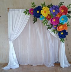 an arrangement of paper flowers is displayed on a white backdrop with sheer draping