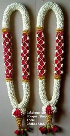 two white and red decorated vases with flowers on the wall in front of them