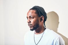 a man with dreadlocks standing in front of a wall and looking off to the side