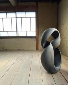 a sculpture sitting on top of a wooden floor next to a window in a room