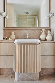 a bathroom with a sink, mirror and vases