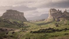 two people riding horses down a path in the middle of a valley with mountains behind them