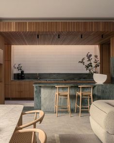 an open kitchen and living room area with bar stools, counter tops, and chairs