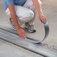 a man kneeling down on the ground with a hose attached to it