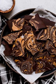 chocolate and peanut butter swirled cookies in a bowl on a plaid table cloth next to a spoon