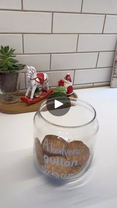 a glass jar filled with rocks sitting on top of a counter next to a potted plant