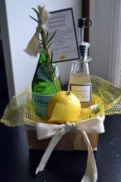 a bottle and some lemons in a wooden box on a table with a white ribbon