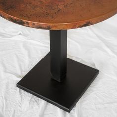 a round metal table on a black pedestal