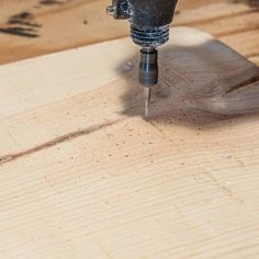 a drill is being used to make a hole in a piece of wood that has been sanded