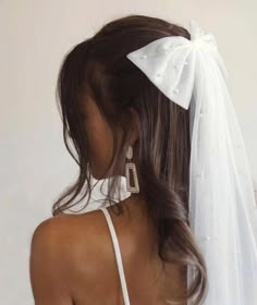 the back of a woman's head wearing a white veil with diamond earrings on it