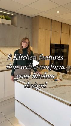 a woman standing in front of a kitchen island with marble counter tops and white cabinets