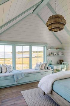 a bedroom with white walls and wooden floors, blue bedding and window seates