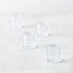 four clear glass cups sitting on top of a table next to each other with holes in them