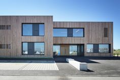 two large wooden buildings sitting next to each other on top of a parking lot in front of a blue sky